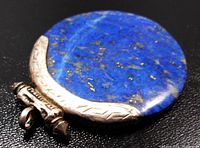 Close-up image showing the blue lapis lazuli stone with silver decoration on the bottom and side edges, with visible etched tribal patterns on silver parts.