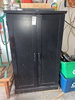 Front view of black laminate cabinet with closed doors and metal handles