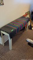 Side angle showing the table with colorful fabric runner covering the top, highlighting the shape and crack in one leg.