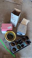 Three small coolers and a box with 1-gallon sprayer placed on ground with stacked planting pots and black plastic seedling tray