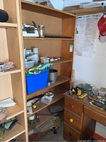 Wood six level shelf with various items on shelves and nearby workbench, used condition.