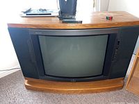 Front view of Sony CRT television with wood frame and integrated speakers, showing screen and side control buttons.