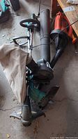 Photo showing two grass trimmers (Certified and Yardworks) and one Black and Decker leaf blower with collection bag.