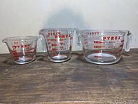 Front view of three Pyrex glass measuring cups with red lettering, arranged by size from small to large