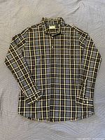 Full view of one men's long-sleeve plaid dress shirt in a black, yellow, and grey checkered pattern