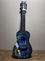 Full front view of the guitar showing colorful circular graphics and lightning bolt design on body.