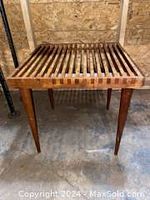 Full view of the wooden slat end table with tapered legs in warehouse environment.