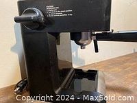 Side angle showing portafilter attached to espresso machine and drip tray below