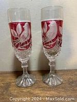 Two ruby red Nachtmann Amaris crystal champagne flutes with bird design