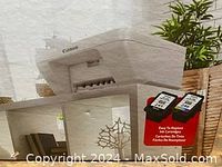 Photo of the Canon printer shown on a display shelf, with packaging highlighting easy-to-replace ink cartridges.