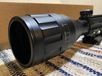 Close-up image showing lens with adjustable magnification ring and markings from 3x to 8x and distance markings up to 150