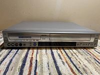 Front view of the silver Sanyo DVD and VCR recorder unit showing main DVD drive and VHS tape slot.
