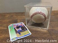 Signed baseball in protective case and baseball card beside it