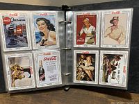 Photo of two open pages of the Coca-Cola advertising book showing multiple vintage adverts from 1947, 1948, 1950, 1951, and 1954.