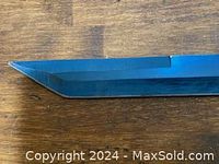 Close-up of the sword blade tip with an angled tanto style point, polished steel blade.