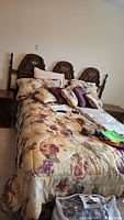 Queen size bed with floral patterned bedding and ornate wooden headboard from left side angle.