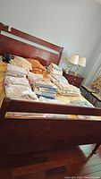 Full view of cherry finish queen bed frame with bedding piled on mattress