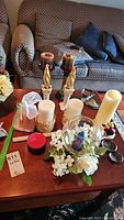 Overview of assorted candles and candle holders on wooden table showing variety and condition