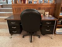 Front view of the vintage metal office desk with the black adjustable office chair positioned behind it.