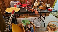 Photo showing the folding table with various decorative and miscellaneous items on top and baskets underneath. Items on table and floor are not included in the lot.