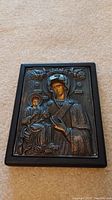 Full front view of icon showing wood frame and silver overlay on carpet background