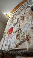 Photo showing large variety of tablecloths, runners and napkins spread on wooden bed frame.