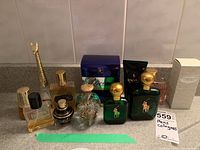 Photo of nine men's cologne bottles including Polo green bottles, a cat-shaped bottle, Boss, and others showing various fill levels and shapes.