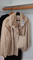 Front view of pearl mink fur jacket on hanger