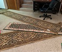Three carpet runners laid out on a carpeted floor near a desk and chair, showing different designs and sizes.