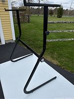 Full view of the black metal adjustable stand showing its Z-shaped base and horizontal support arms.