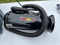 Black cylindrical DataVac 3 vacuum with a flexible hose coiled around it, showing the main unit and hose details.