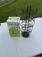Metal wire egg holder rack and boxed vintage Benriner Cook Help vegetable spiral cutter on white table outdoors.