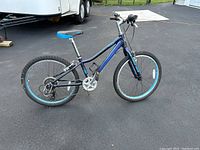 Side view of dark blue Liv Enchant 24 Lite kids' bike on asphalt surface