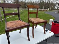 Two American Federal style side chairs made of curly maple with woven rope seats, displayed on a white table outdoors.