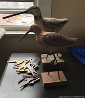 Photo showing two wooden bird figures with metal legs on bases, and several bird cutout decorations laid out on table
