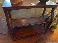 Front view of the wooden bookshelf showing the V-shaped middle shelf and lower shelf against a neutral background.