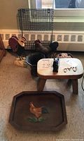 Overall view of items including wire shelf, cast iron rooster and squirrel door stops, wooden step stool, woven frog figurine, and wooden tray with painted rooster.