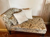 Side angle of the chaise lounge with pillows visible on top, showing the upholstery pattern and shape.