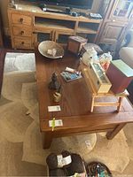 Front view of solid wood coffee table with drawer and various decorative items on top. Shows wood grain and drawer placement.