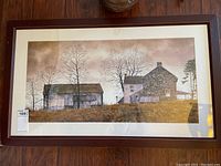 Framed signed print showing rural landscape with stone house and barn under leafless trees