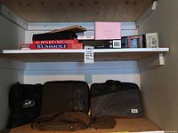 Shelf with various boxed board games including Poker and Rummoli, and multiple laptop bags beneath shelf