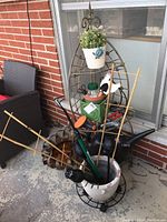 Full lot showing metal corner stand with pots, bamboo lattices, gardening tools, and sun tin decoration leaning against wall.