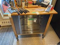 Front view showing butcher block top, three metal drawer fronts and casters
