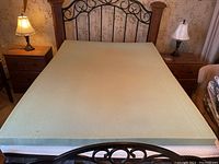 Memory foam mattress topper laid flat on bed frame illustrating full rectangular shape and size.