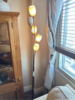 Front view of five-light floor lamp with curved arms and three shades lit