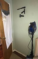 Wall mounts holding vacuum cleaner accessories including extension wands and attachments.