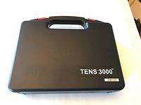 Closed black carrying case labeled TENS 3000 with handle and red locking tabs