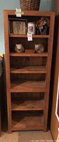 Front view of the wood display shelf showing six fixed shelves with some decorative items on top shelves, in natural wood finish.