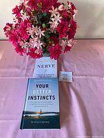 Image showing flower vase with pink and red artificial flowers and two books on a pink surface.