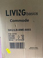 Photo of the front side of the boxed Living Basics commode showing product details and SKU information.